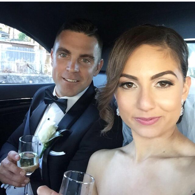 Bride and groom having celebratory drink inside a luxury wedding car