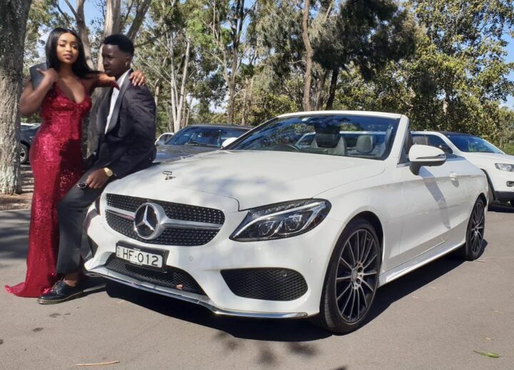 Young couple taking photos beside coordinated luxury vehicles