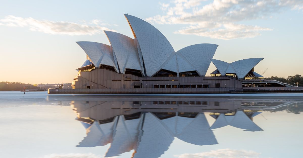 A photo of the Sydney Opera House while being reflected in the water.
