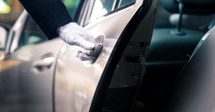 A chaffeur opening the car door for the guests.