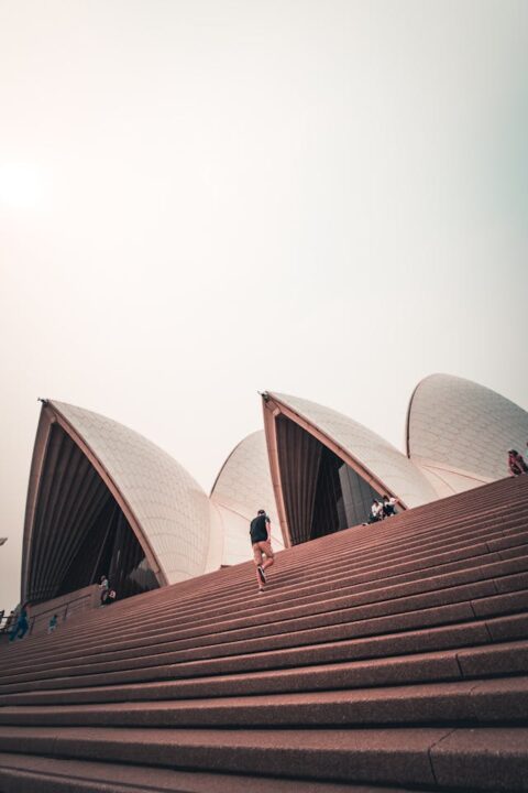 A man walking up towards the Sydney Opera House.